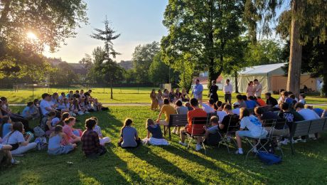 Abschlussfoto aller Beteiligten des Jugendtreffens im Stift Kremsmünster auf der Bühne im Zelt mit Jesus Bild und Text: "Jesus, ich vertraue auf dich"