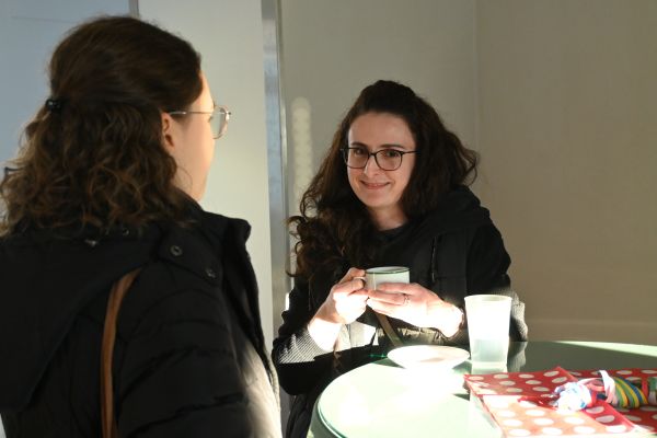 Portraitaufnahme einer jungen Frau beim Kaffeetrinken am Stehtisch. Sie lächelt freundlich in die Kamera.