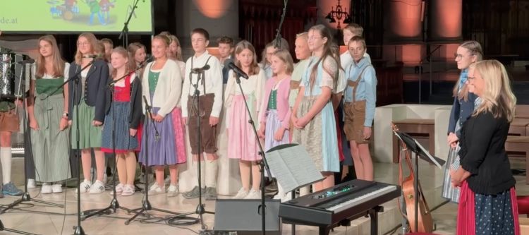 Gruppe von Schülerinnen und Schüler stehend, festlich gekleidet, mit Klavier rechts im Bild