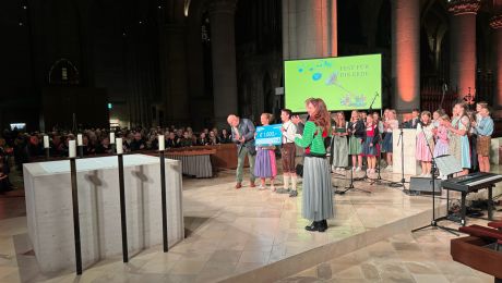 Gruppe von Schülerinnen und Schüler in großem Kirchenraum, links im Bild ein Altar, in der Mitte eine Sprecherin