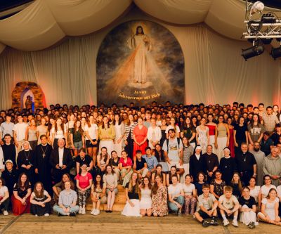 Abschlussfoto aller Beteiligten des Jugendtreffens im Stift Kremsmünster auf der Bühne im Zelt mit Jesus Bild und Text: "Jesus, ich vertraue auf dich"