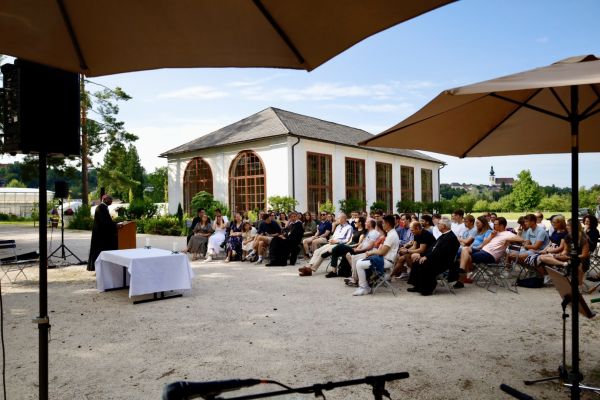 Versammlung zur heiligen Messe beim Treffpunkt Benedikt Sommerfest vor dem Feigenhaus. Blick von der Musikband. Sonnenschirme spenden Schutz.