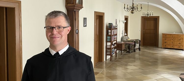 Mönch in schwarzem Ordensgewand in einem Gang