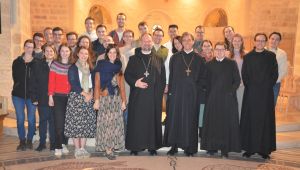 Gruppe von jungen Leuten mit zwei Äbten und zwei Mönchen in einer Kirche