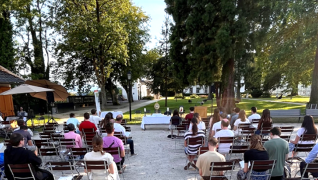 Junge Christen sitzen in Richtung aller Heiligstes im Stiftsgarten und warten auf den Beginn der heiligen Messe.