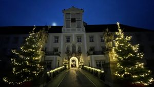 beleuchteter Torbogen mit Durchfahrt, rechts und links beleuchtete Christbäume