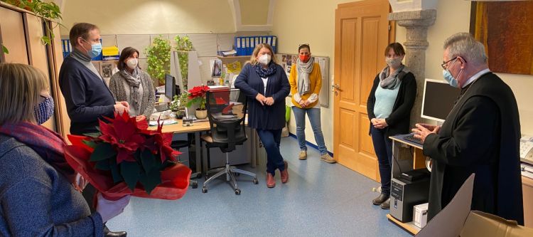 kleine Gruppe von Personen im Halbkreis stehend im Büro