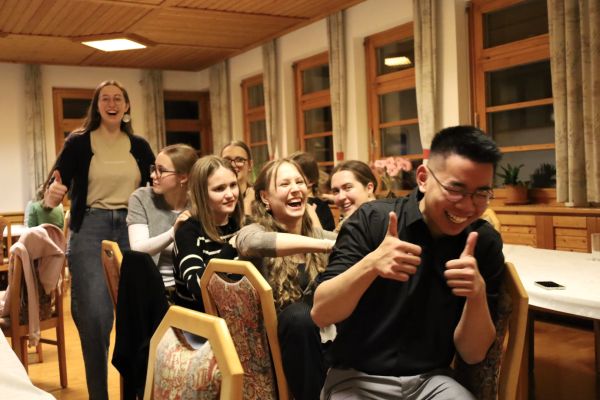 Spiel und Spaß beim Treffpunkt Benedikt: junge Leute massieren sich in einer langen Reihe gegenseitig. Ganz vorne genießt und lacht ein junger Postulant und streckt beide Daumen nach oben 