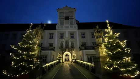 beleuchteter Torbogen mit Durchfahrt, rechts und links beleuchtete Christbäume