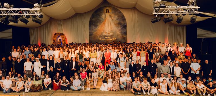 Abschlussfoto aller Beteiligten des Jugendtreffens im Stift Kremsmünster auf der Bühne im Zelt mit Jesus Bild und Text: "Jesus, ich vertraue auf dich"