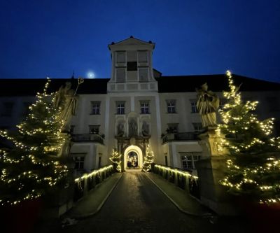 beleuchteter Torbogen mit Durchfahrt, rechts und links beleuchtete Christbäume