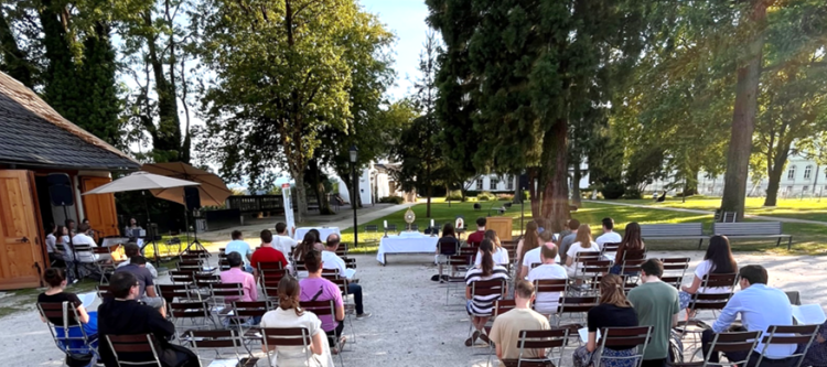 Junge Christen sitzen in Richtung aller Heiligstes im Stiftsgarten und warten auf den Beginn der heiligen Messe.