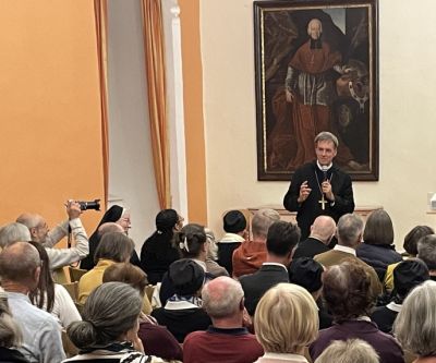 ein Redner und sitzende Personen, die bei einem Vortrag zuhören