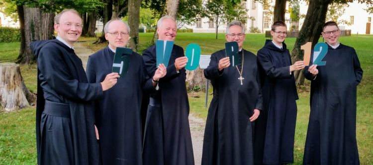 sechs Benediktiner Mönche mit Schriftzeichen fünf vor zwölf in den Händen haltend