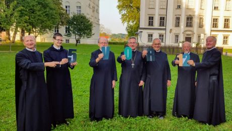 sieben Benediktiner Mönche mit Schriftzeichen fünf vor zwölf in den Händen haltend